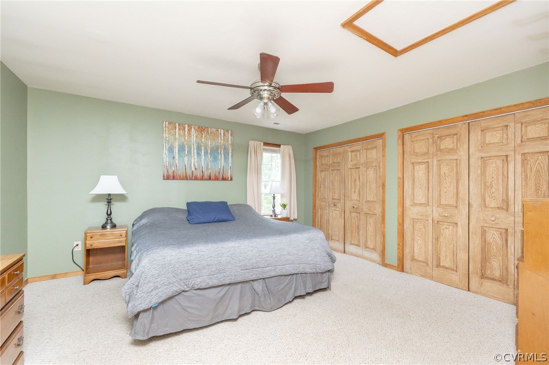 Bedroom with ceiling fan, carpet, and two closets