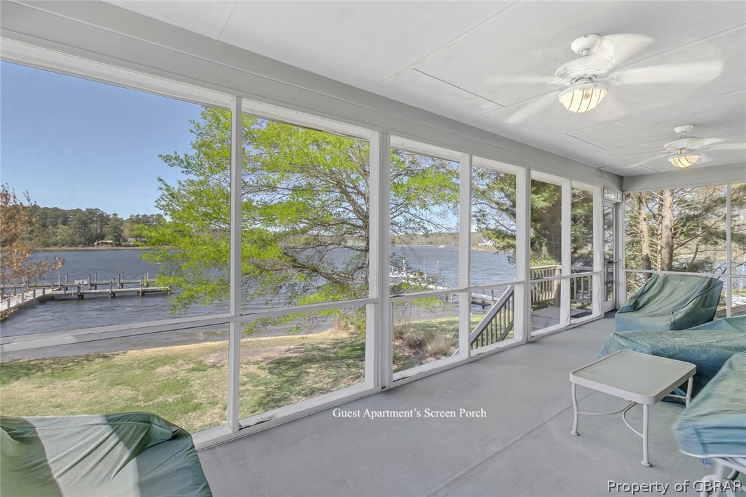 Unfurnished sunroom featuring a water view, plenty of natural light, and ceiling fan