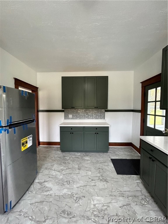 Kitchen with light tile flooring, tasteful backsplash, and fridge