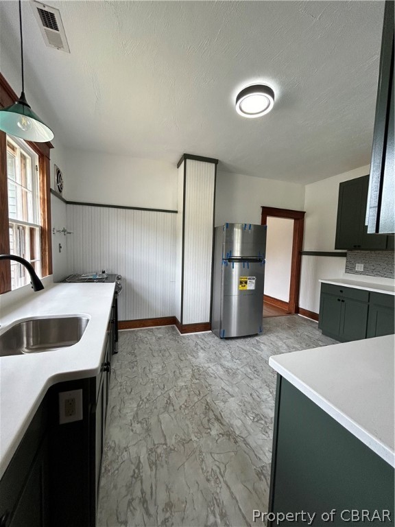 Kitchen with hanging light fixtures, light tile floors, sink, and fridge