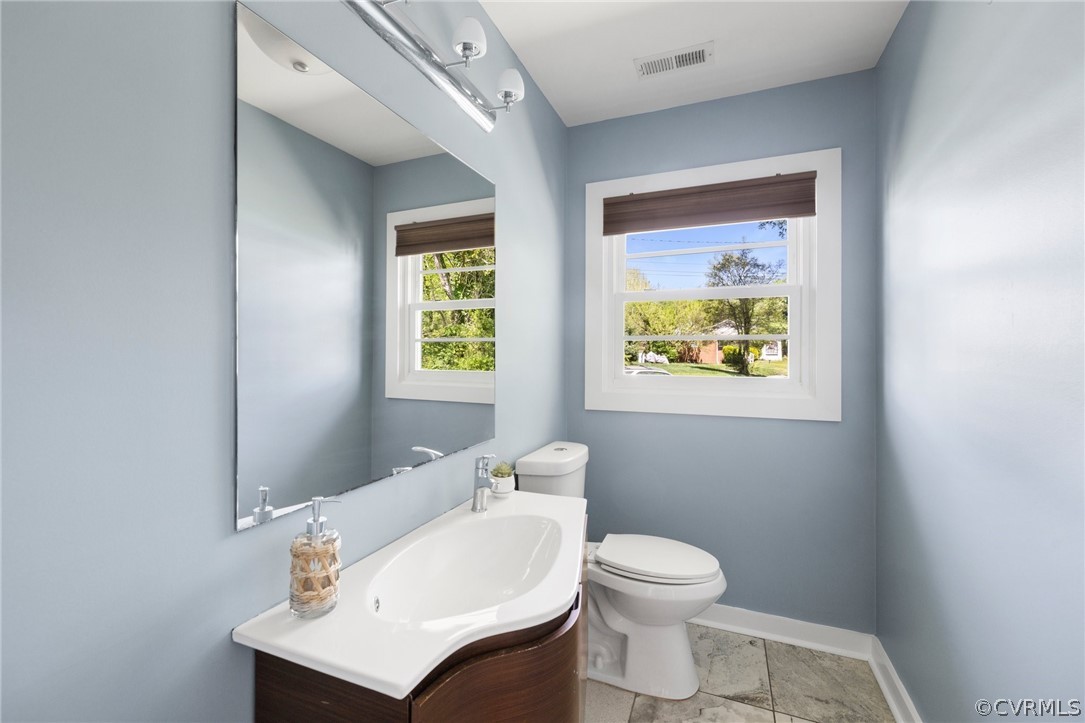 Bathroom with tile flooring, vanity, toilet, and a wealth of natural light