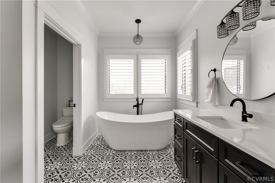 Bathroom featuring a bath, toilet, tile flooring, vanity, and ornamental molding