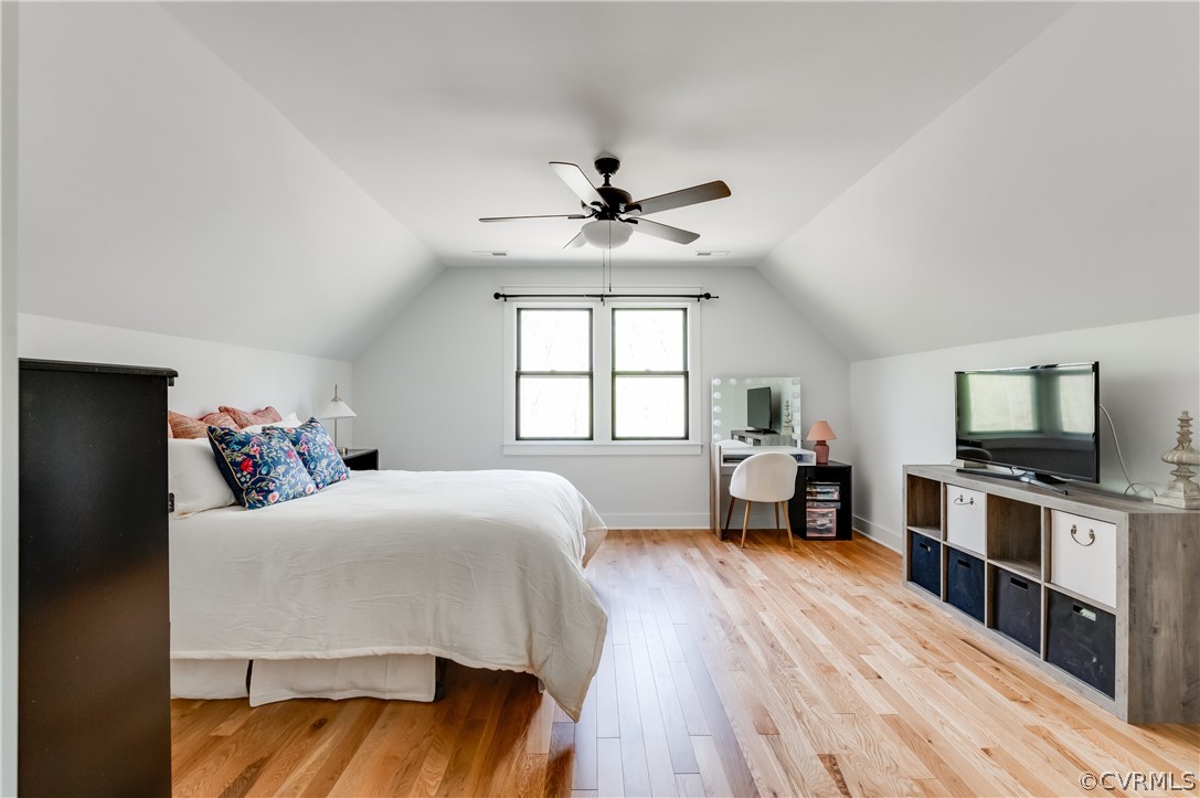 Bedroom featuring ceiling fan, vaulted ceiling, and light wood-type flooring