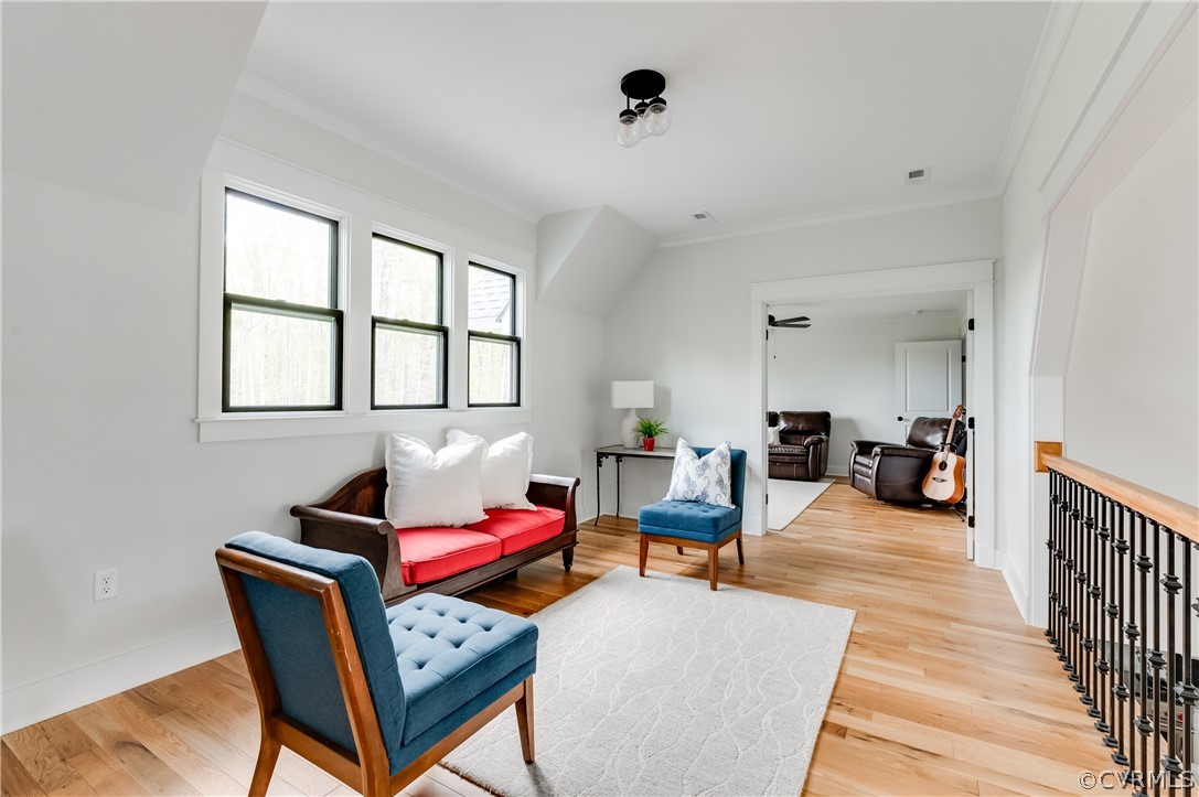 Sitting room with ornamental molding and light hardwood / wood-style floors