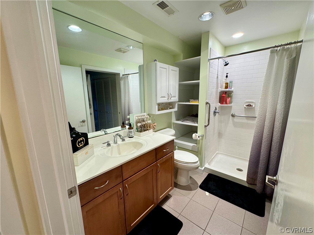 Bathroom featuring a shower with shower curtain, vanity, tile floors, and toilet