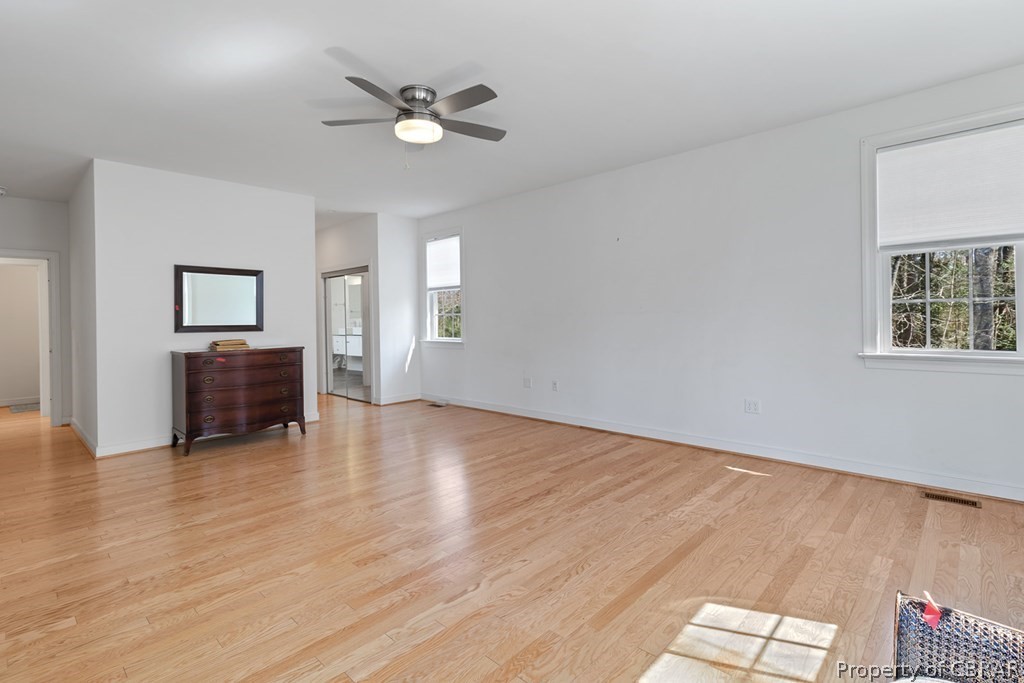 Unfurnished room featuring plenty of natural light, ceiling fan, and light wood-type flooring