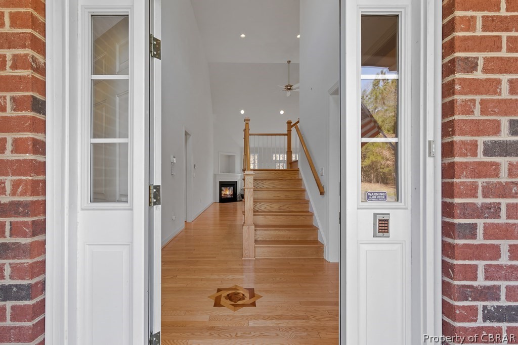 Foyer entrance with brick wall, light hardwood / wood-style floors, ceiling fan, and a fireplace