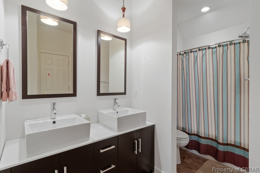 Bathroom featuring toilet, double vanity, and tile flooring