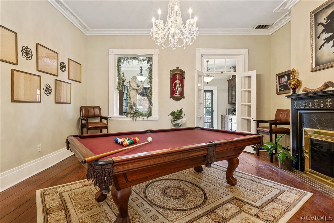 Rec room with ornamental molding, billiards, and dark wood-type flooring