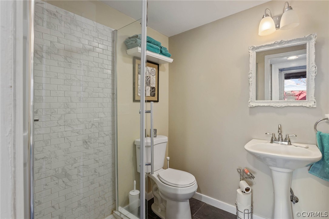Bathroom with an enclosed shower, toilet, and tile floors
