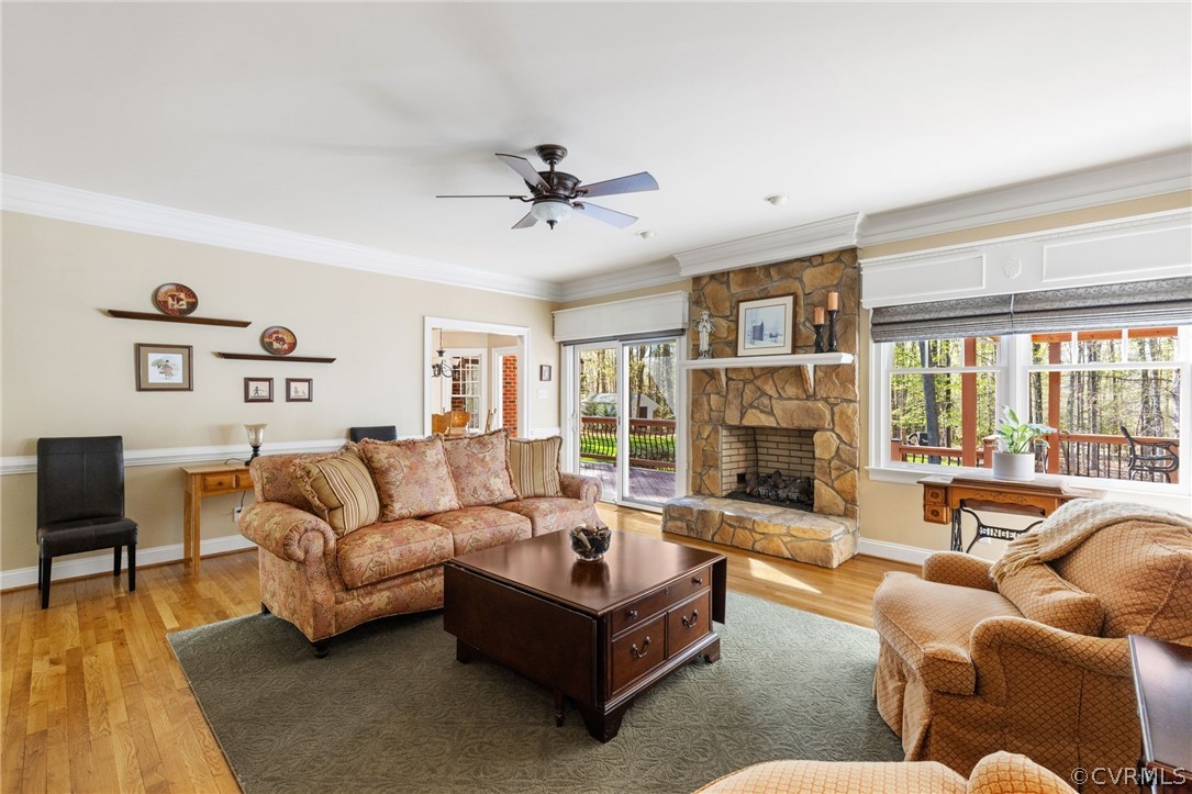 Living room with plenty of natural light, a stone fireplace, and hardwood / wood-style floors