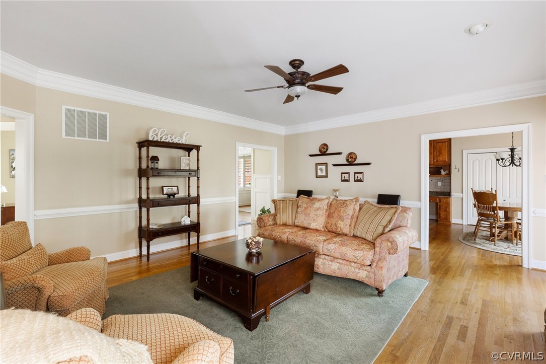 Living room featuring light hardwood / wood-style floors, crown molding, and ceiling fan