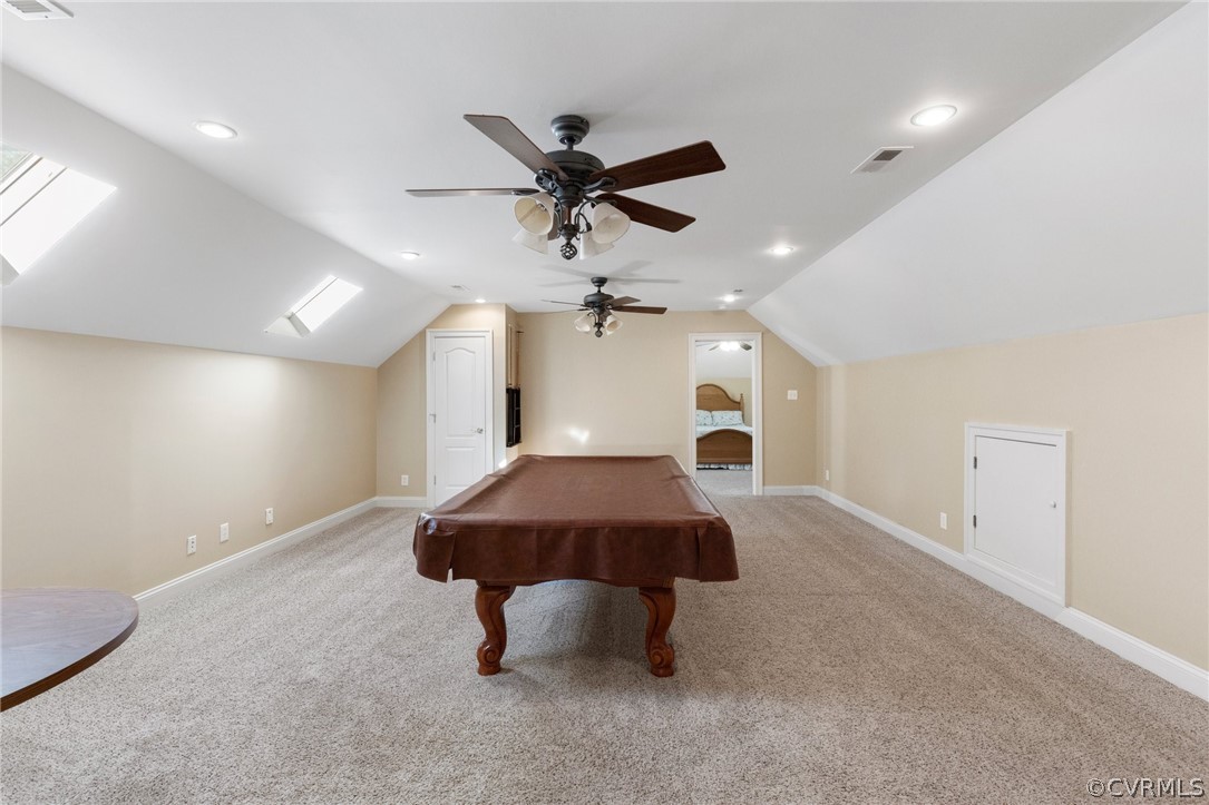 Rec room featuring light carpet, vaulted ceiling with skylight, ceiling fan, and billiards
