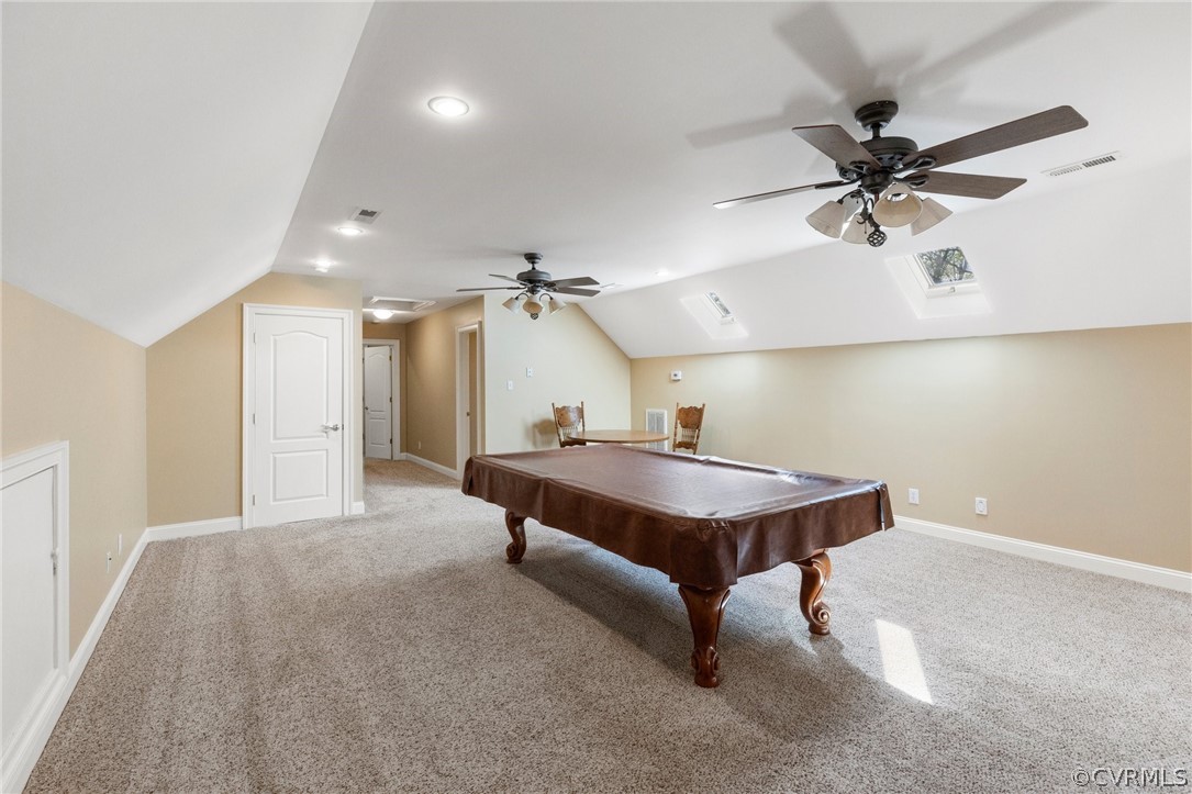 Recreation room with light colored carpet, lofted ceiling with skylight, ceiling fan, and billiards