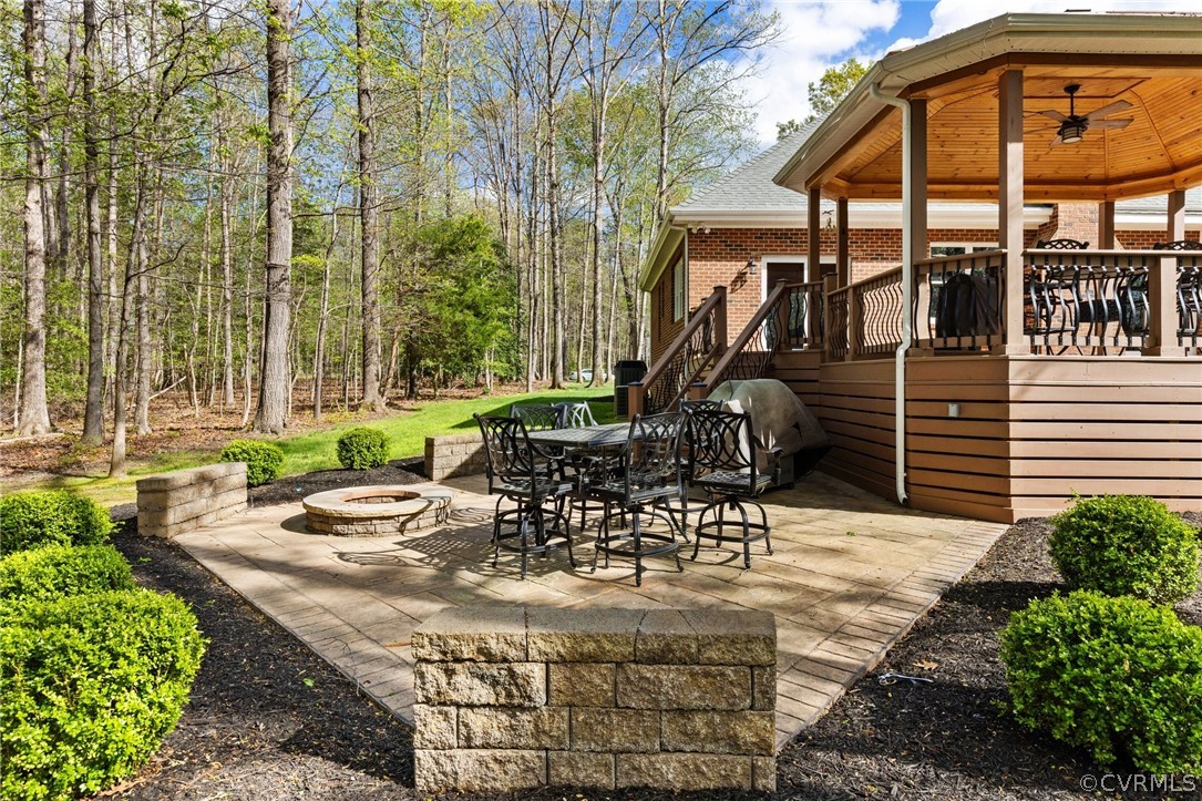 View of terrace with a deck, an outdoor fire pit, area for grilling, and ceiling fan