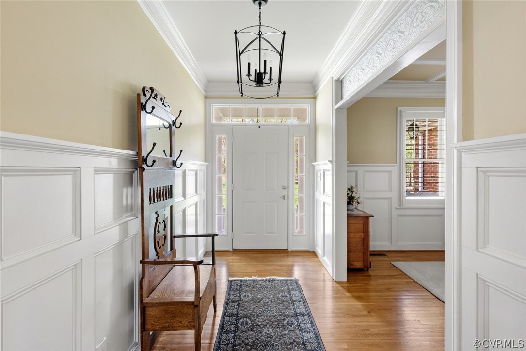 Entryway featuring a wealth of natural light, ornamental molding, light hardwood / wood-style flooring, and an inviting chandelier