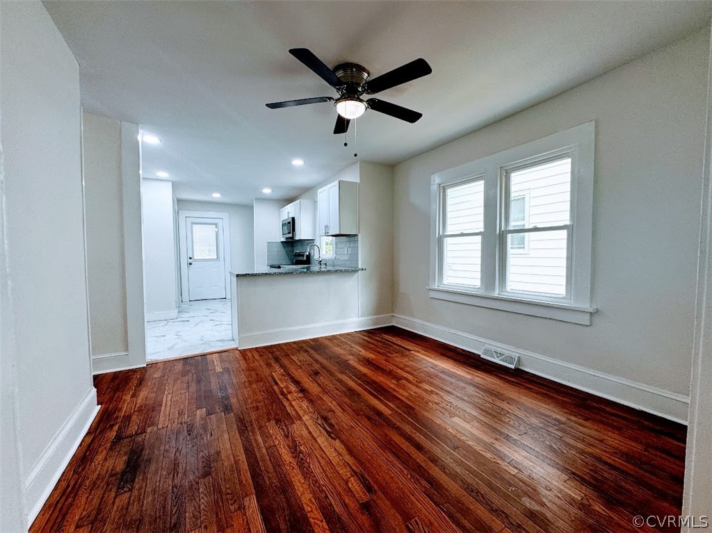 Unfurnished living room featuring ceiling fan, sink, and dark hardwood / wood-style flooring