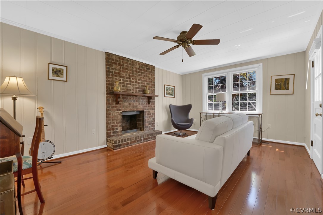 Family room featuring ceiling fan, a brick fireplace, light hardwood floors and entrance to the backyard!