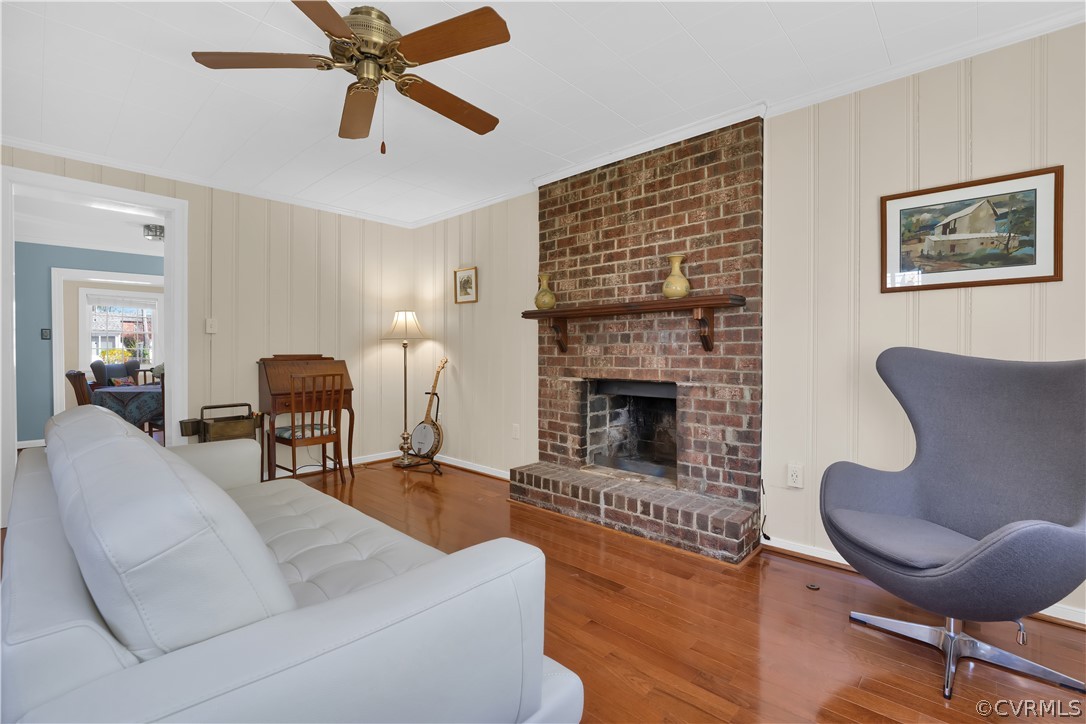 Family room featuring ceiling fan, a brick fireplace, light hardwood floors and entrance to the backyard!