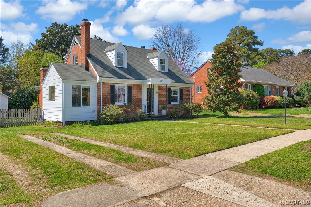 Brick Cape Cod style home with a front lawn and off street parking.