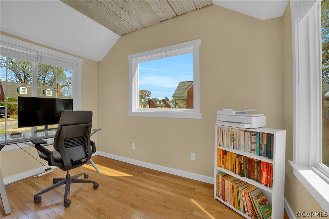 Office area featuring lofted ceiling, beautiful natural light, hardwood floors, and its own mini-split system!