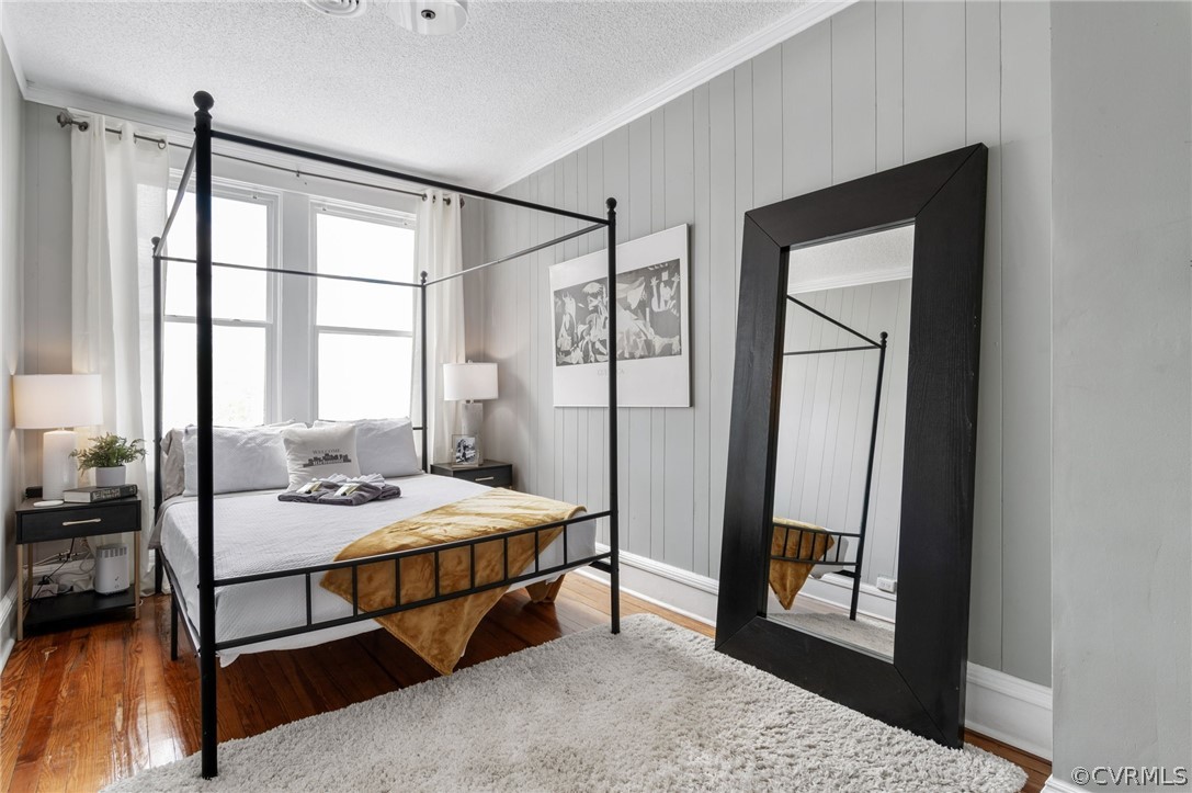 Bedroom featuring a textured ceiling, dark wood-type flooring, and ornamental molding