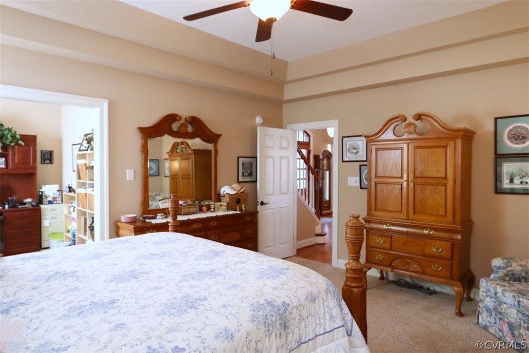 Bedroom with light carpet, ceiling fan, and ensuite bath
