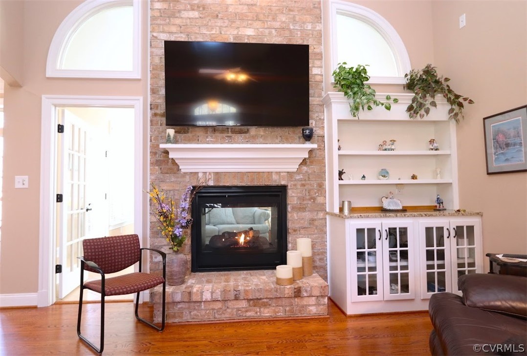 Great room with a wealth of natural light, wood flooring, and a brick fireplace