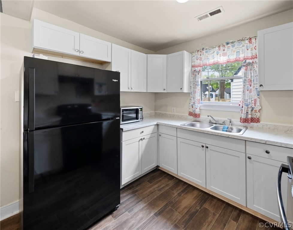 Kitchen featuring white cabinets, black fridge, and sink