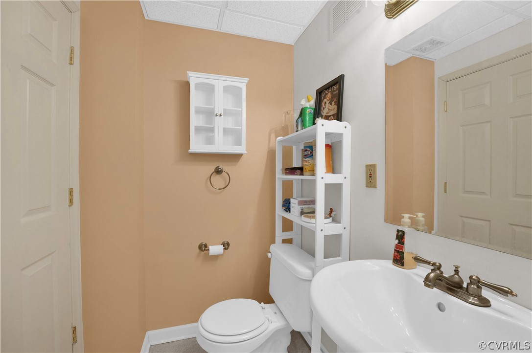 Bathroom featuring sink, toilet, a paneled ceiling, and tile flooring
