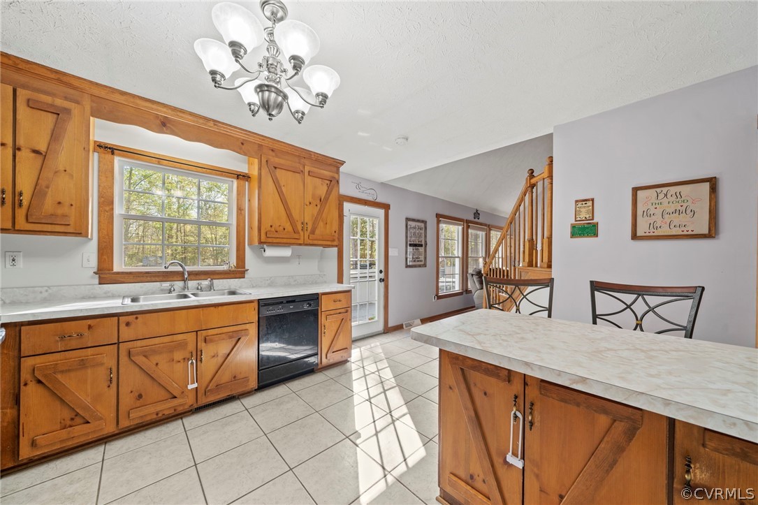 Kitchen featuring sink, black dishwasher, light tile floors, and a wealth of natural light