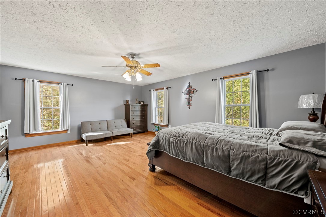 Bedroom featuring ceiling fan, a textured ceiling, and light wood-type flooring