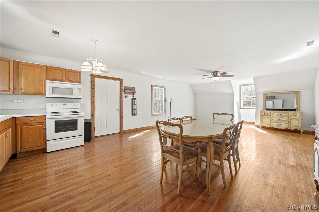 Dining space with light hardwood / wood-style flooring and ceiling fan with notable chandelier
