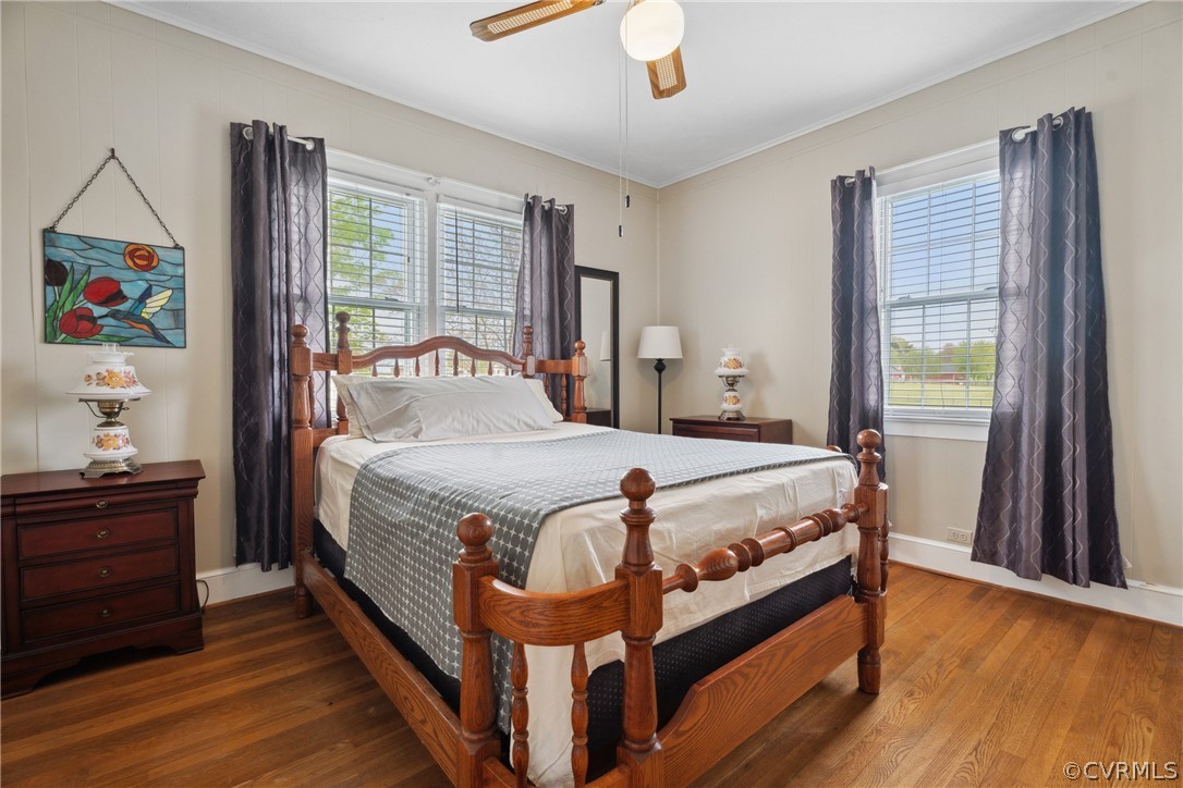 Bedroom featuring ornamental molding, ceiling fan, hardwood / wood-style floors, and multiple windows