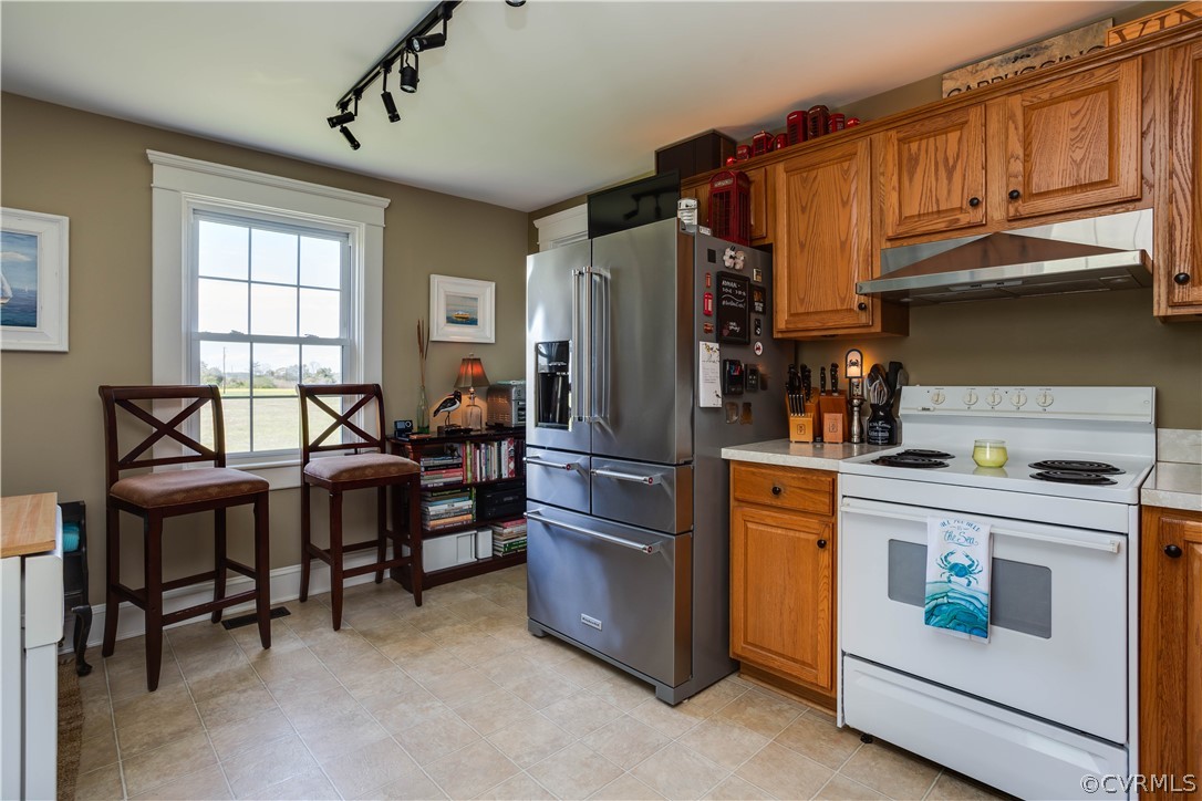 Kitchen featuring rail lighting, electric range, high end refrigerator, and light tile floors
