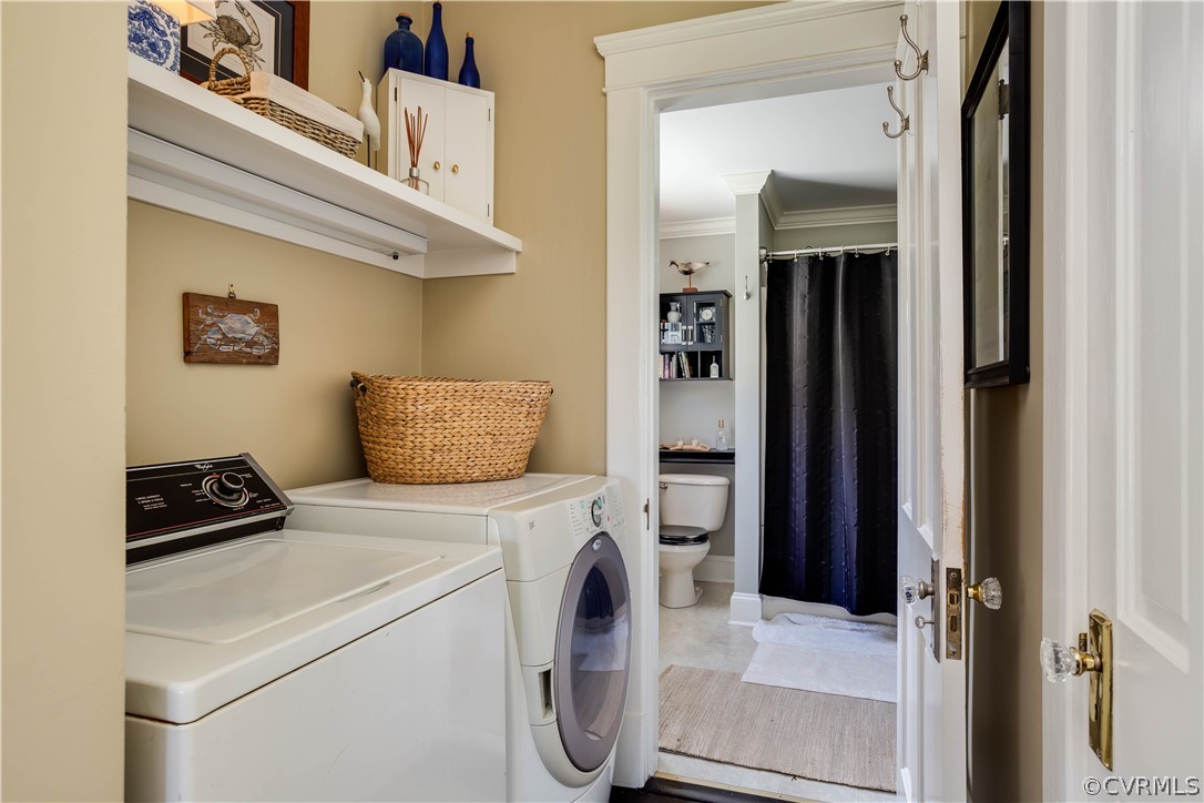 Clothes washing area with tile flooring, cabinets, separate washer and dryer, and ornamental molding