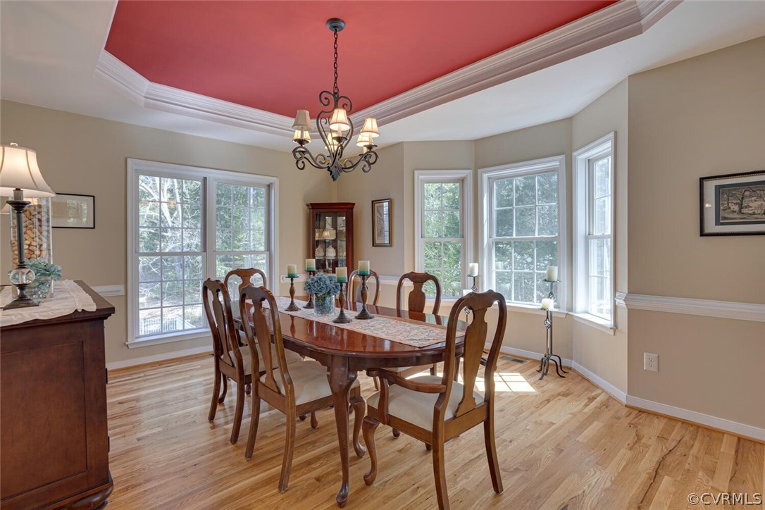 Formal dining room with tray ceiling, bay window, and floor to ceiling rear windows that give a birds-eye view of the pool and backyard.