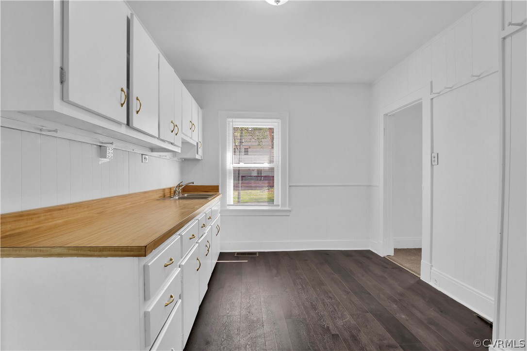 Kitchen featuring sink, white cabinetry, and dark wood-type flooring