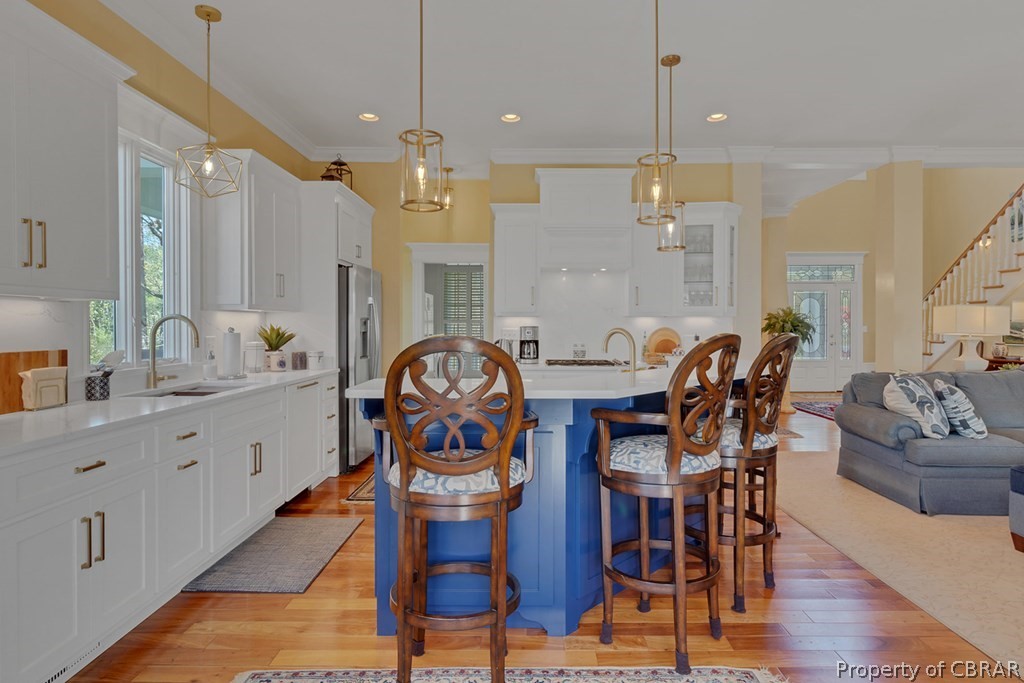 Kitchen featuring hanging light fixtures, white cabinetry, and a kitchen bar