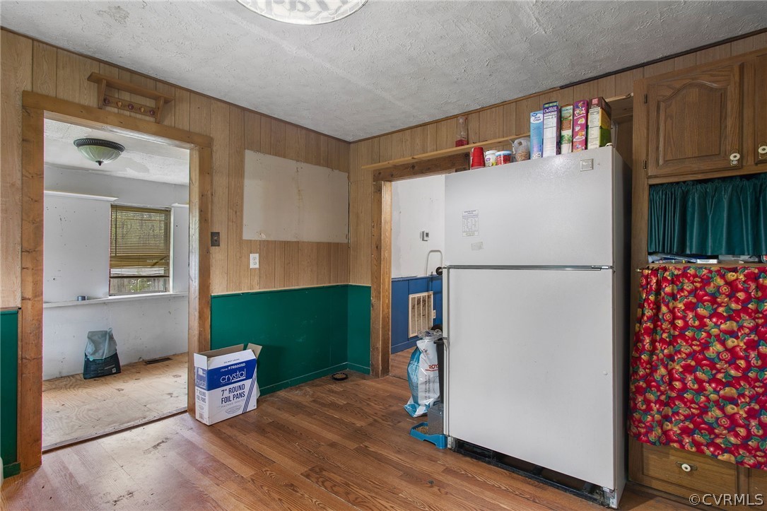 Kitchen with white fridge, a textured ceiling, and hardwood / wood-style flooring