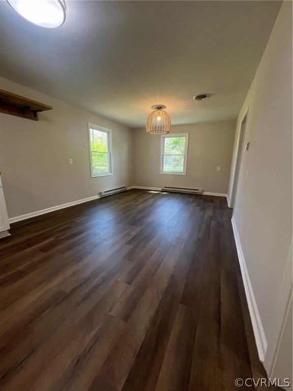 Unfurnished room with plenty of natural light, dark wood-type flooring, and a baseboard radiator