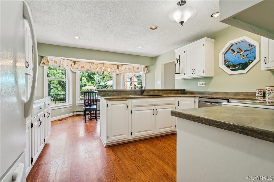 Kitchen featuring white cabinets, sink, dishwasher, white refrigerator, and hardwood / wood-style flooring