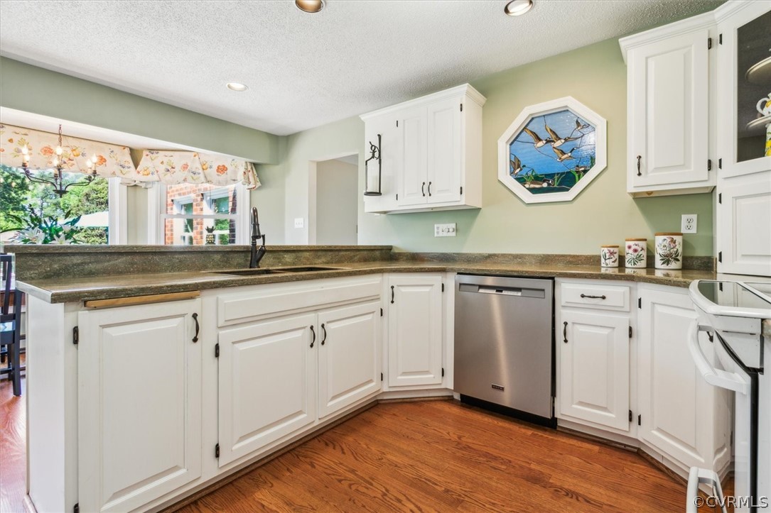 Kitchen featuring kitchen peninsula, dishwasher, hardwood / wood-style flooring, white cabinets, and sink