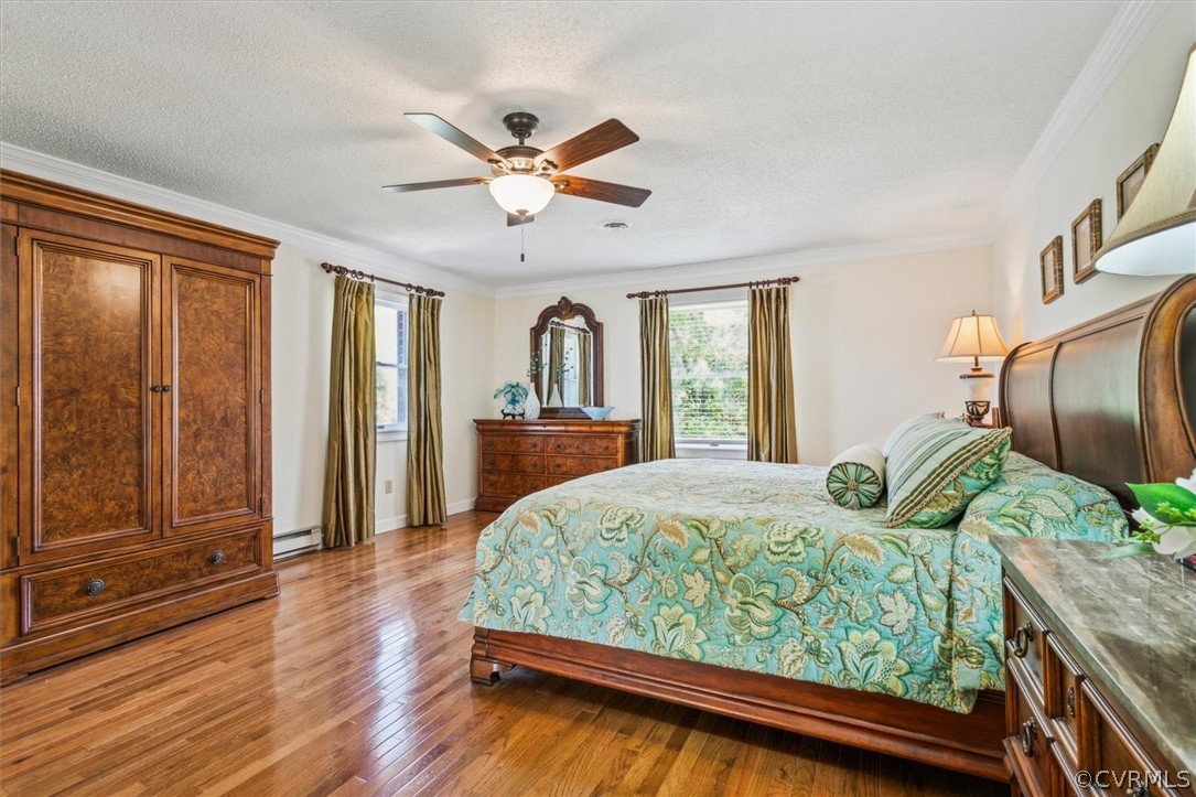 Bedroom with hardwood / wood-style flooring, ornamental molding, ceiling fan, and a textured ceiling