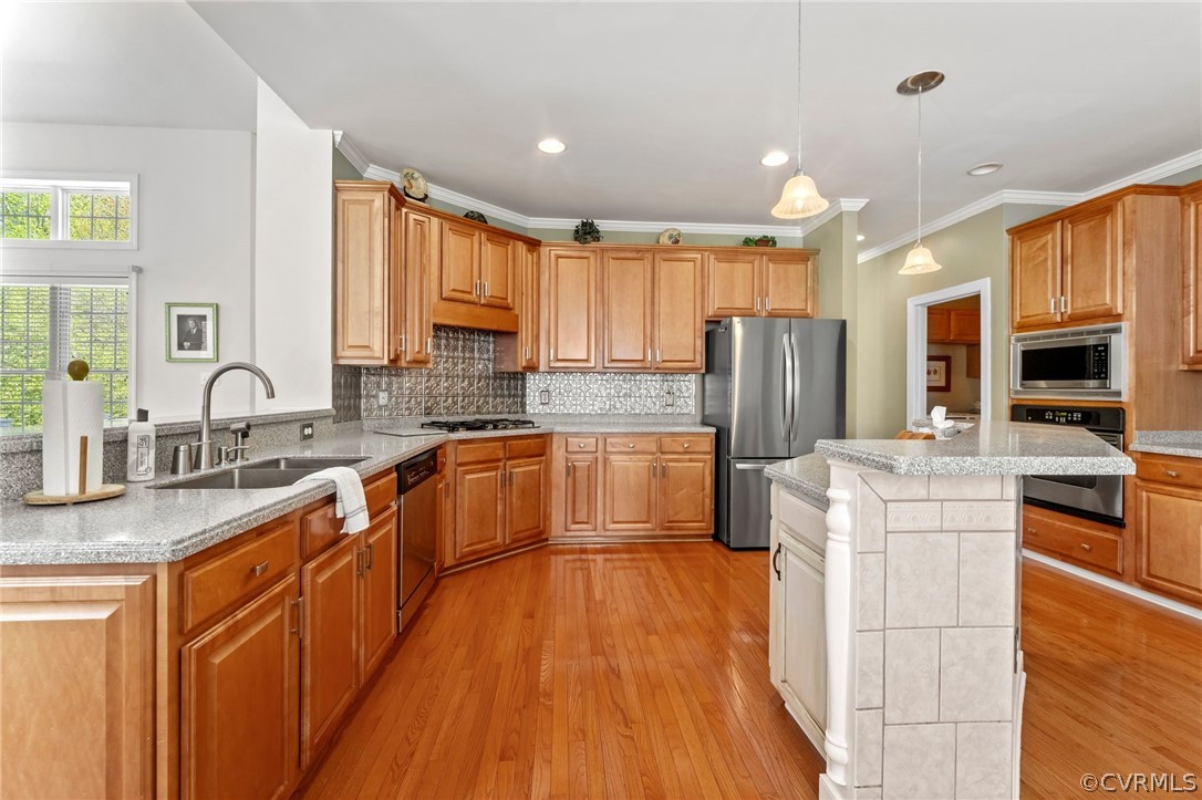 Kitchen with a kitchen island, light hardwood / wood-style flooring, backsplash, and stainless steel appliances
