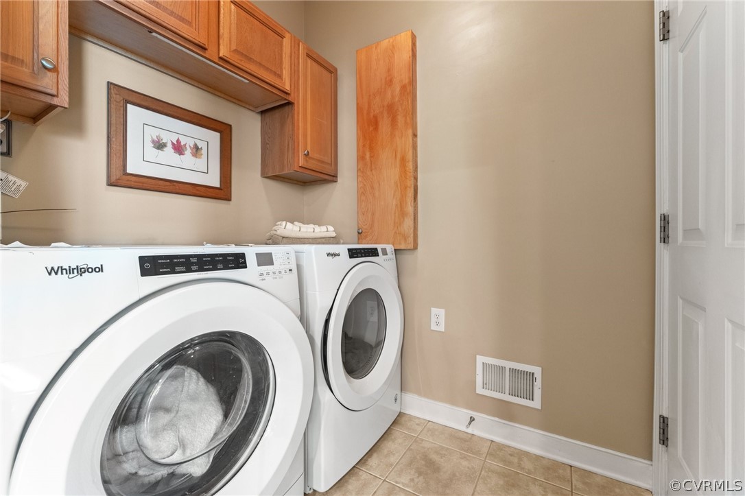 Laundry area with cabinets, light tile flooring, and washer and clothes dryer