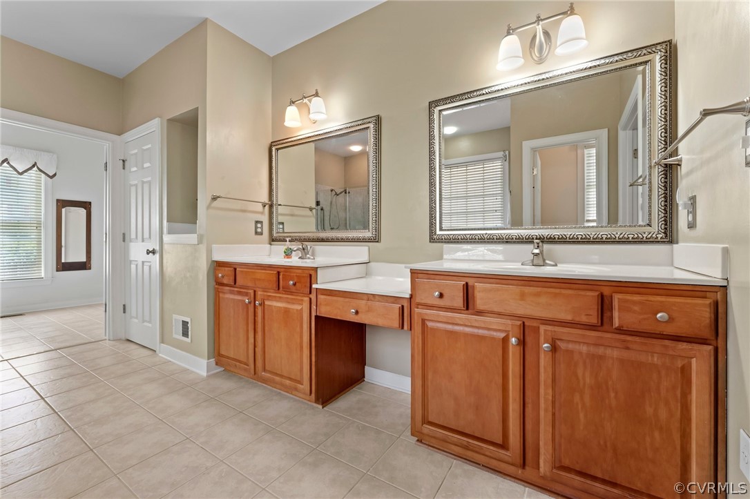 Bathroom with double vanity, plenty of natural light, and tile floors