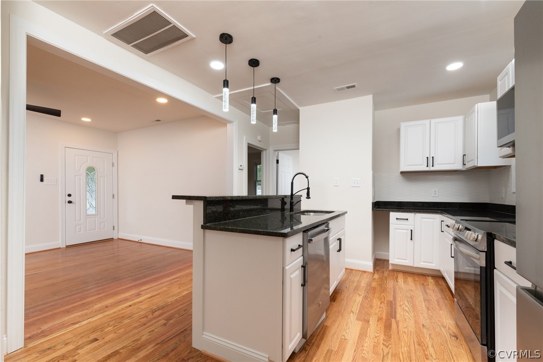 Kitchen featuring white cabinets, hanging light fixtures, and light hardwood / wood-style floors