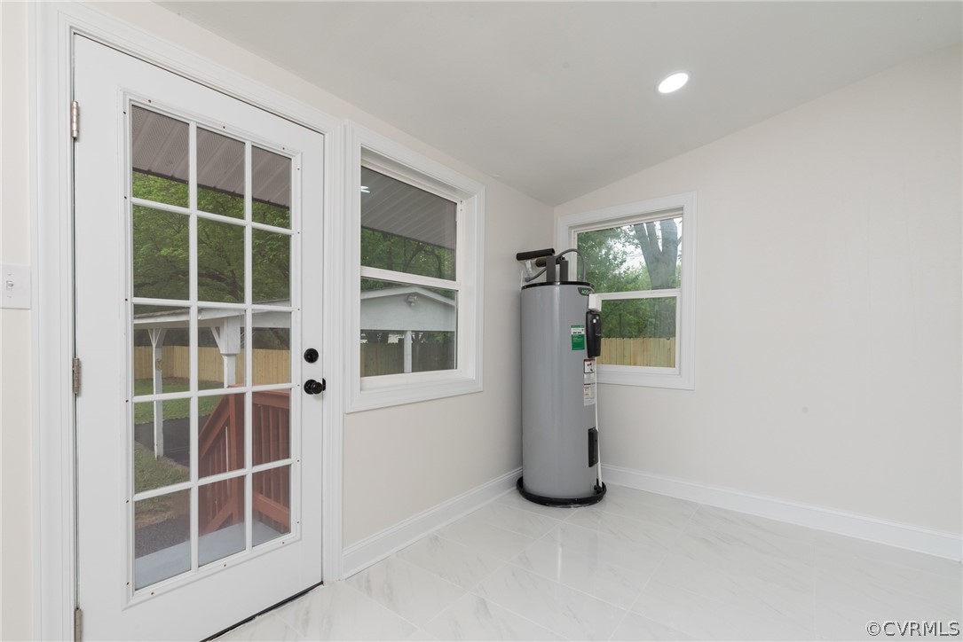 Doorway featuring vaulted ceiling, electric water heater, and light tile floors