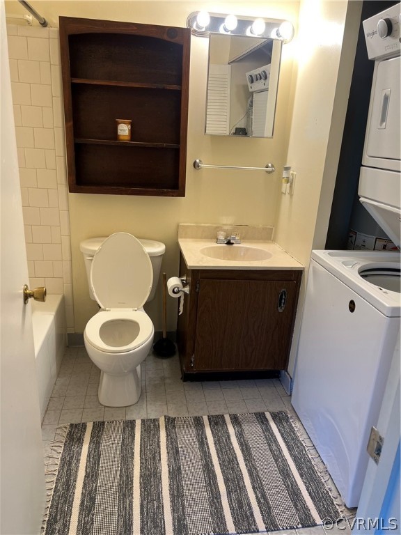 Full bathroom with  shower combination, stacked washer / dryer, oversized vanity, tile flooring, and toilet